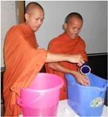 Two monks practice washing their hands with soap