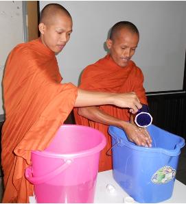 Two monks practice washing their hands with soap